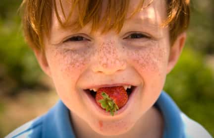 little boy with strawberry on his mouth