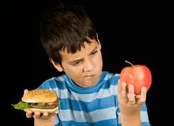 little boy holding a burger and apple